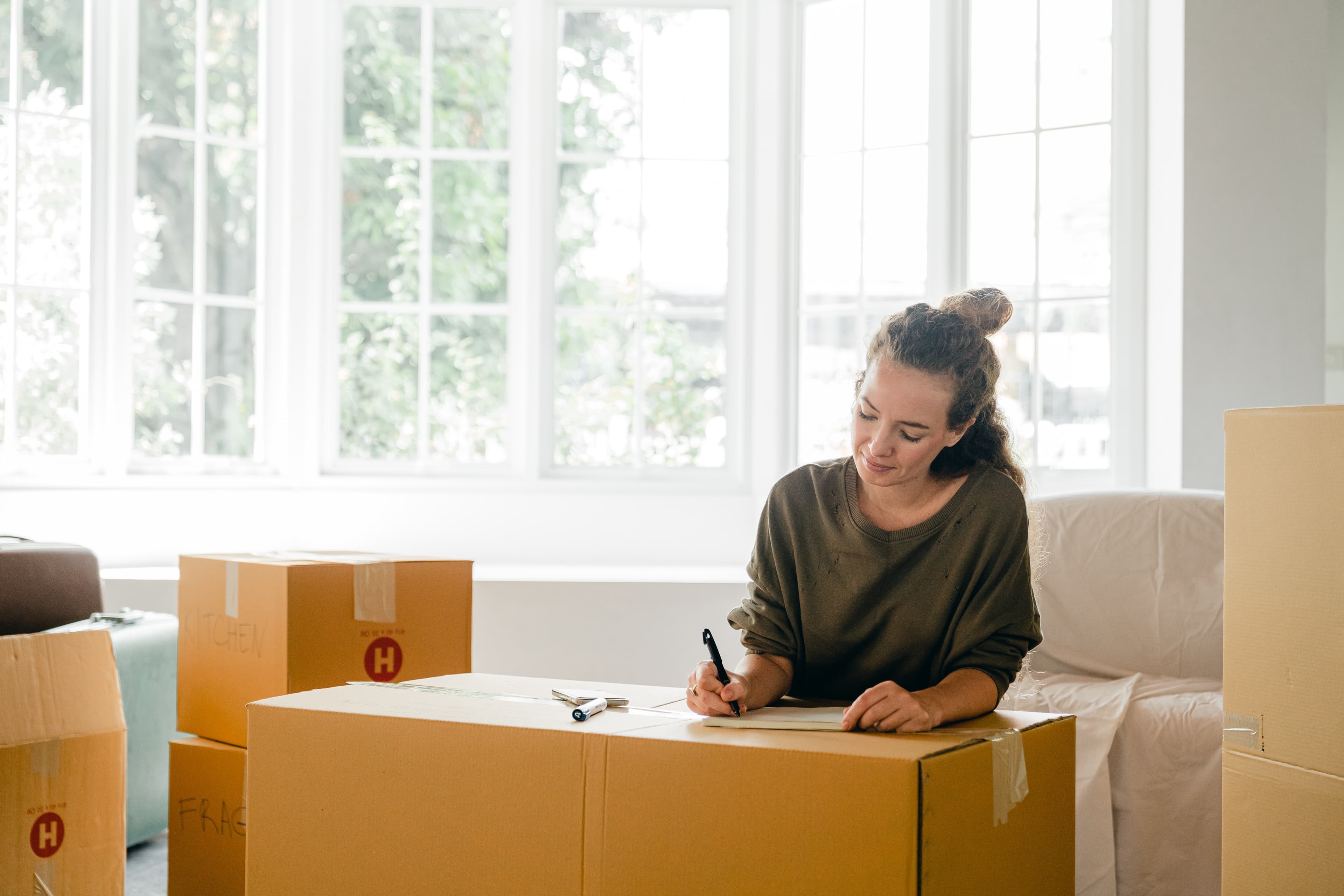 Woman writing on a box by a window